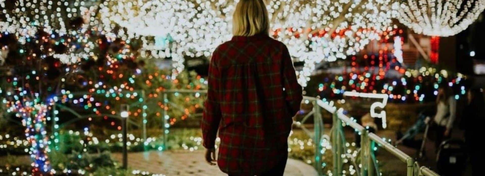 Woman walking on path towards lighted tree display