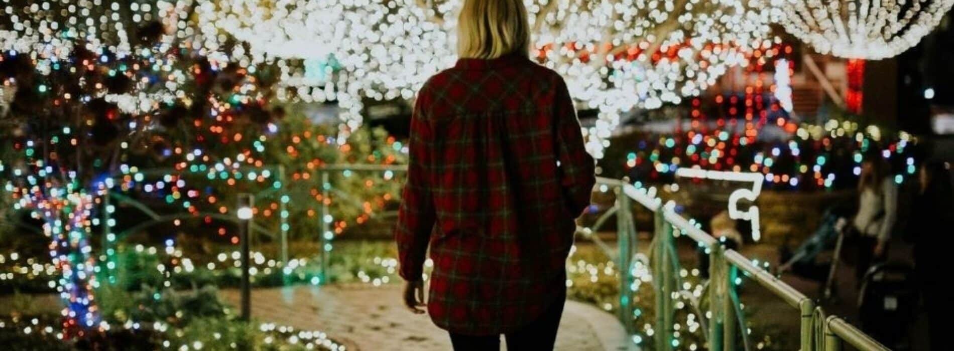 Woman walking on path towards lighted tree display