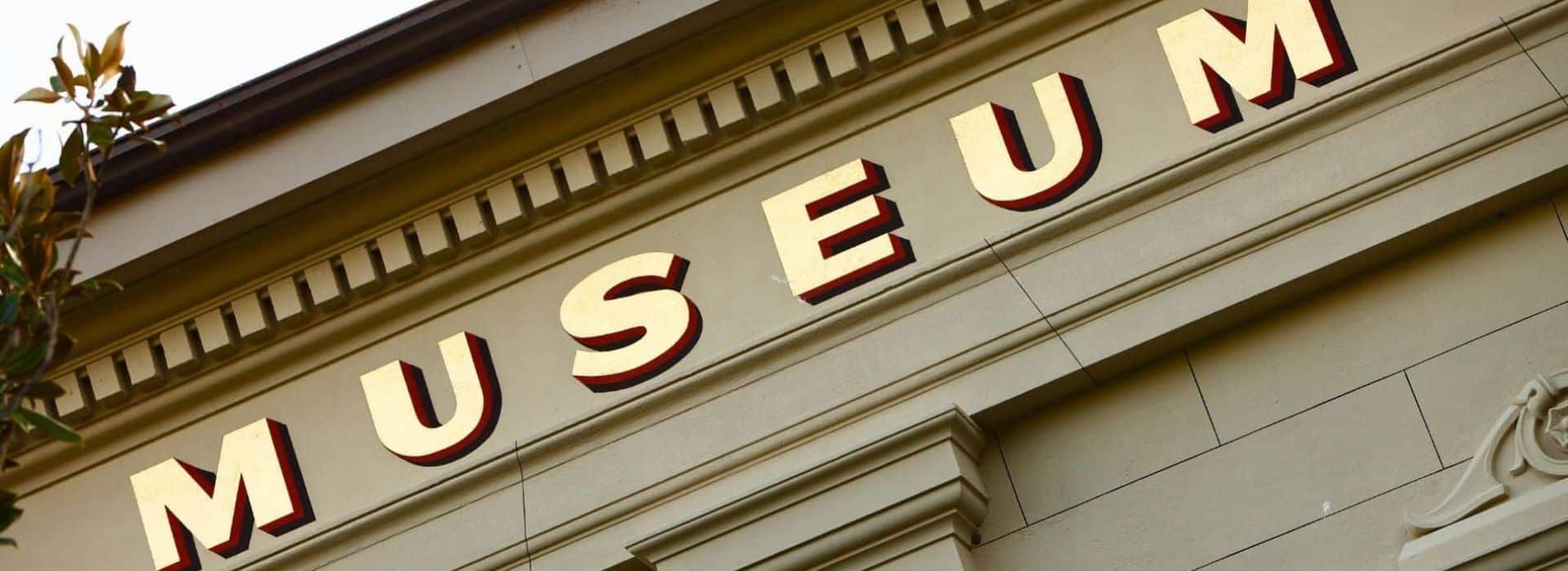 museum sign on building with tree branch in daylight