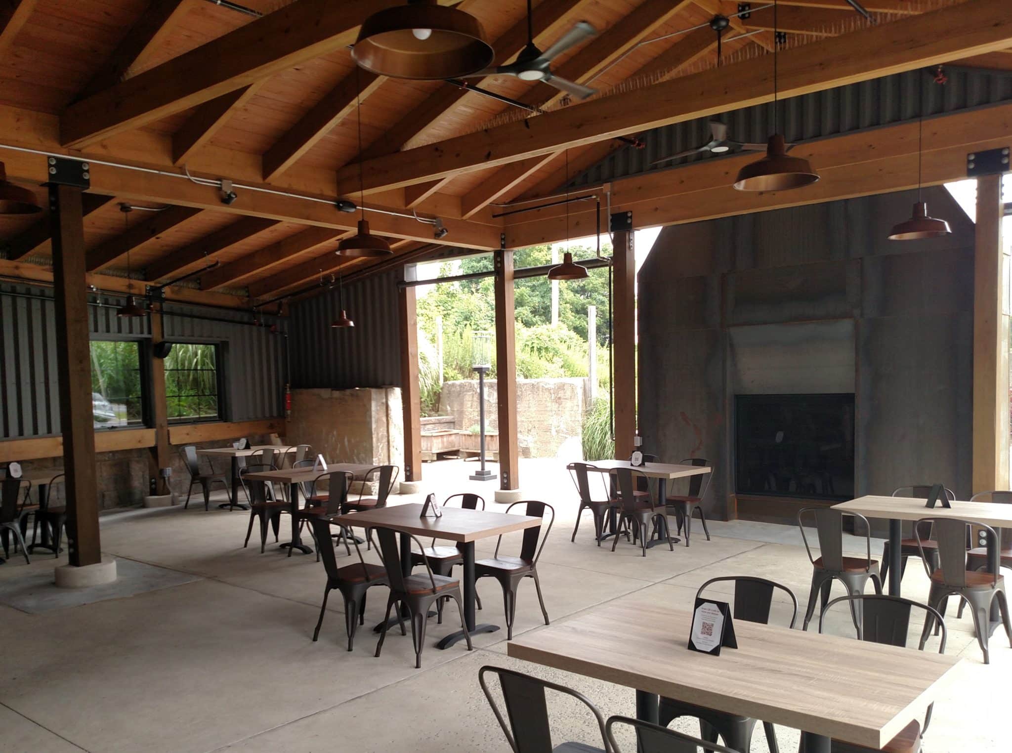 outdoor dining area with timber frame roof and fireplace