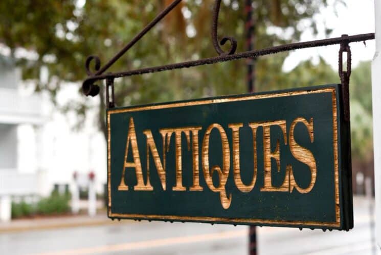 An ornate black wood antiques sign