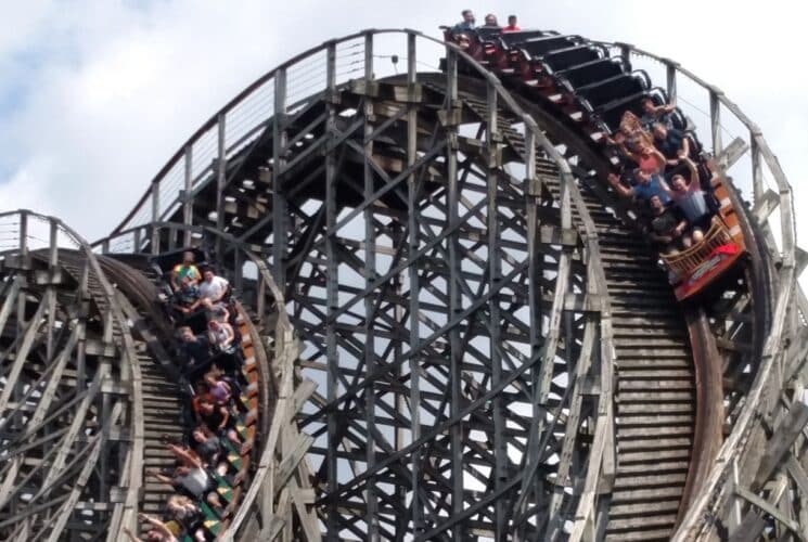 Two cars of roller coasters coming down a hill on wooden roller coaster tracks