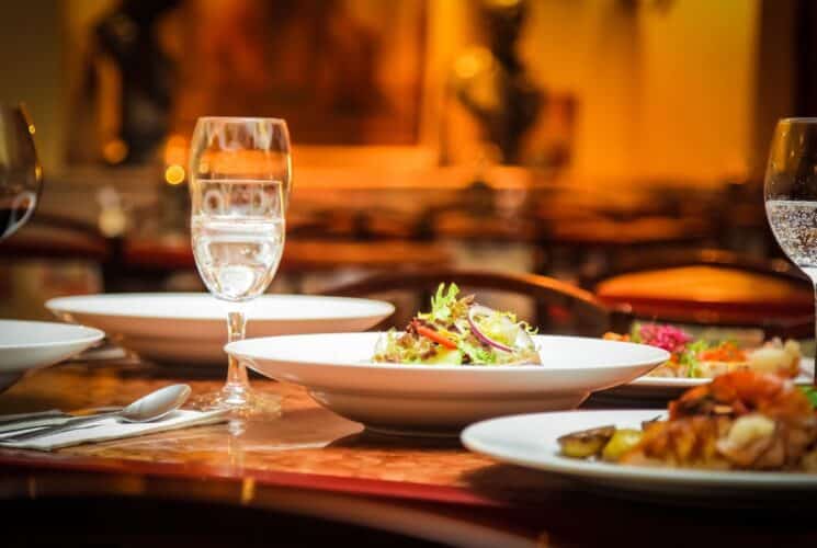 Restaurant table with plates of food and glasses of wine under soft golden lighting