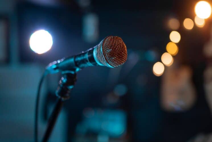 A single microphone on a stand in a room with little white lights and dim lighting