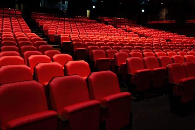 Empty rows of red theatre chairs in a large theatre