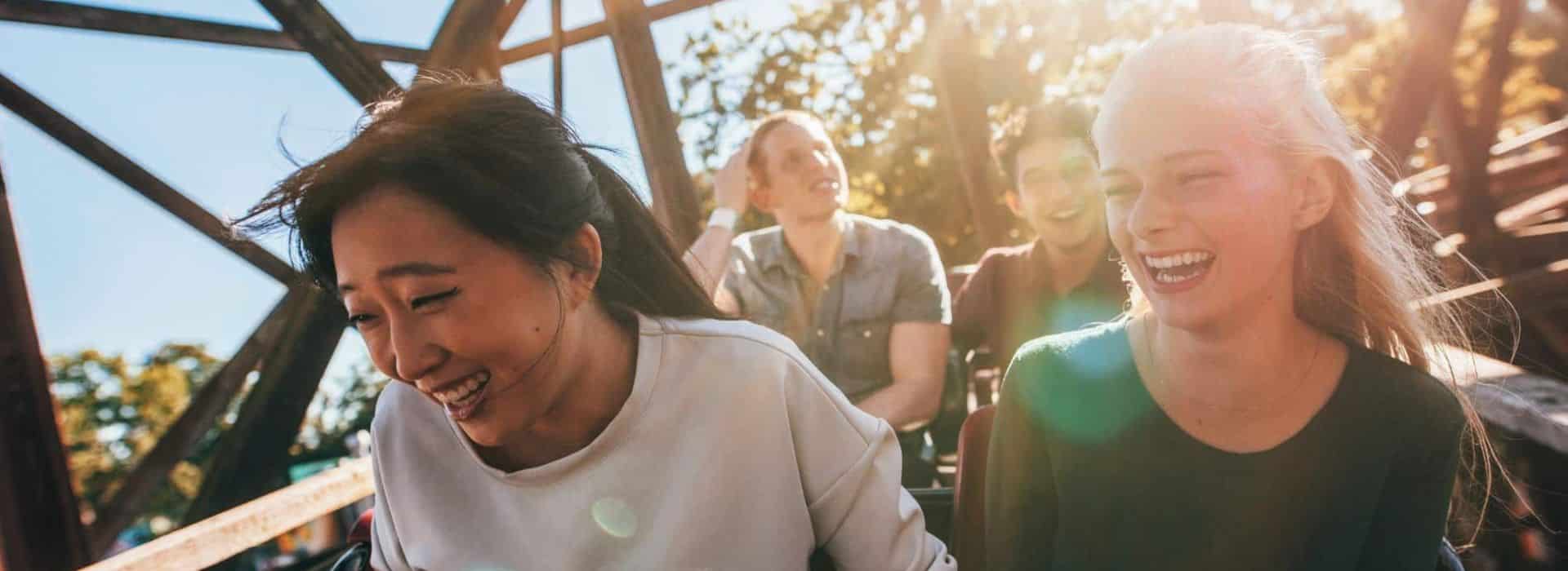 Four people riding in a roller coaster car