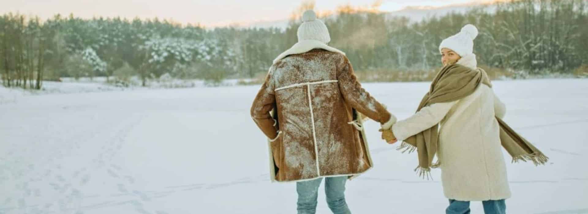 couple holding hands skating on forest lake